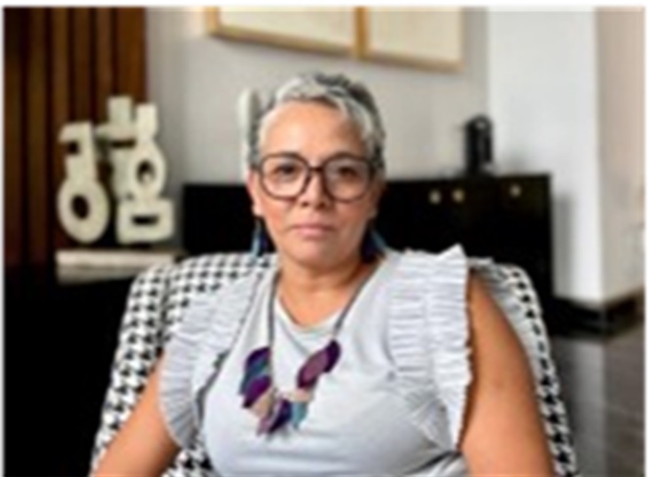  E la imagen se muestra una mujer sentada en una silla, parece estar mirando a la cámara,Ella es Alejandra Acevedo Placeres,  directora de Grupo Pro Niñez A.C, se dedica a mejorar la vida de los niños y niñas en Puebla a través de programas de protección infantil y educación inclusiva,promoviendo la igualdad de género y luchando por un entorno seguro y amoroso para todas las infancias.